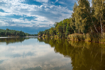 Beautiful view of the lake with blue sky, clouds, and green trees