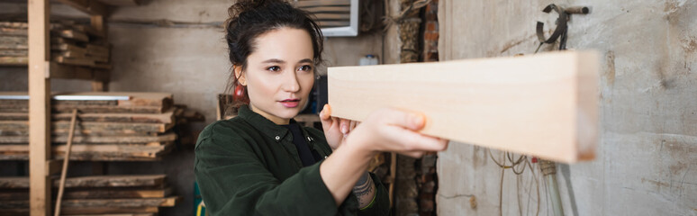 Carpenter checking wooden plank in workshop, banner.