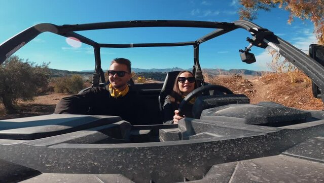 Young couple driving a buggy UTV ATV Can-am polaris on desert off-road in Ronda, Spain, on a sunny day . Couple having fun riding a ATV off-road