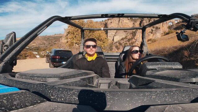 Young couple driving a buggy UTV ATV Can-am polaris on desert off-road in Ronda, Spain, on a sunny day . Couple having fun riding a ATV off-road
