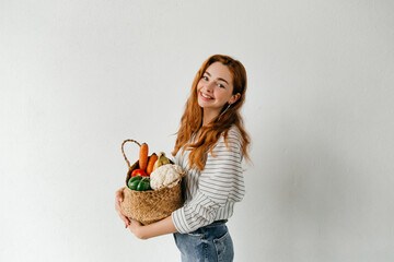 Healthy vegetarian woman holding a basket full of fruit and vegetables. Grocery shopping concept