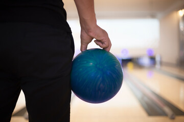 Obraz premium Man hand holding a blue bowling ball with copy space