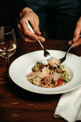 Man twirls spaghetti with fork and spoon
