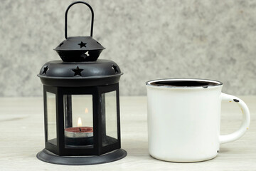 Ornamental Arabic lantern with burning candle glowing and cup of coffee on wood table. Festive greeting card. Invitation for Muslim holy month