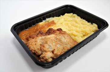 Pollack fried in batter with potatoes in a plastic container. Lunch in a disposable dish.