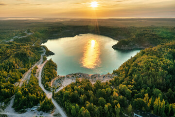 Lake and beach with beautiful blue turquoise water surrounded by green forest at golden sunrise....