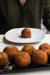 Deliciosa croqueta redonda en un plato, con el plato lleno de croquetas en primer plano.