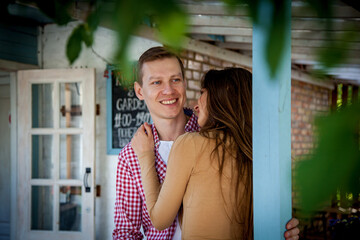 The guy with a girl hugs near a wooden house