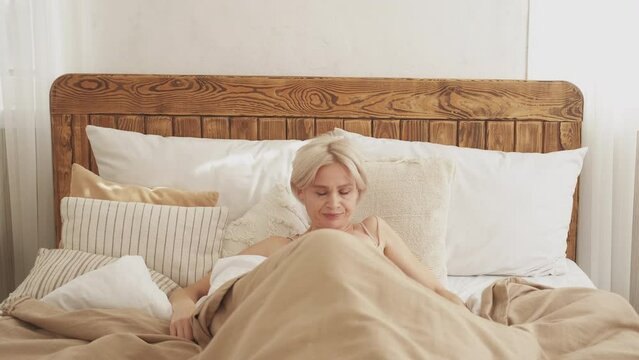 Bad morning. Angry woman. Uncomfortable sleep. Displeased lady spinning on inconvenient bed impossible to rest light home interior.