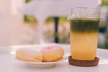 Iced green tea with honey and lemon in a take-away plastic cup and donut in a plate.Homemade...