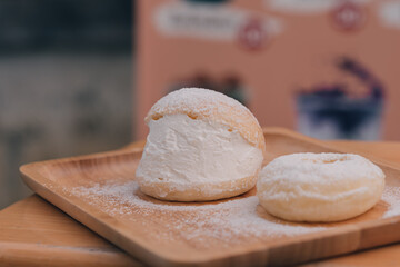 Soft buns filled with creamy are placed in a wooden dish sprinkled with icing sugar.Homemade confectionery,bakery business,baking school or cafe concept,high-energy snacks containing starch and sugar.