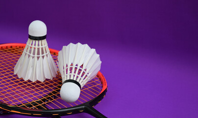 White cream badminton shuttlecocks, badminton rackets on purple floor of indoor badminton court, soft and selective focus on shuttlecock, concept for badminton sport lovers around the world