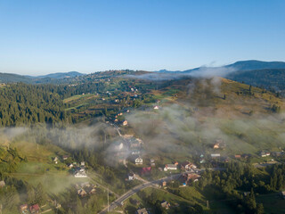 Mountain settlement in the Ukrainian Carpathians in the morning mist. Aerial drone view.