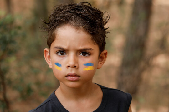 ritratto di un un bambino in contesto naturale  con la bandiera dell'Ucraina disegnata sul viso