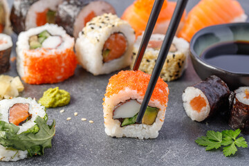 Sushi with avocado, surimi and capelin caviar with chopsticks on stone board.