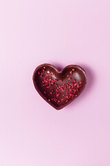 Chocolate heart with freeze-dried berries on a pink background. Creative flatlay for your business.