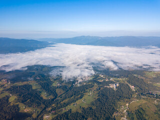High flight in the mountains of the Ukrainian Carpathians. Fog in the valley. Aerial drone view.