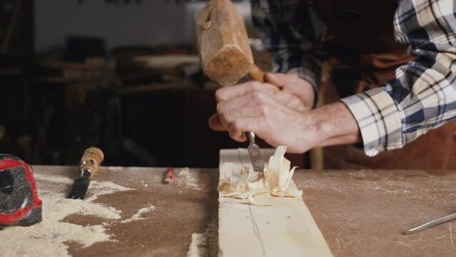 Skilled carpenter carving wood with hammer and chisel. High quality 4k footage