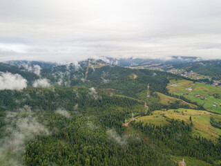 Fototapeta na wymiar Green slopes of Ukrainian Carpathian mountains in summer. Cloudy morning, low clouds. Aerial drone view.