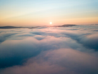 Naklejka na ściany i meble Sunrise over the fog in the Ukrainian Carpathians. Aerial drone view.