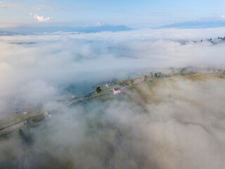 Mountain settlement in the Ukrainian Carpathians in the morning mist. Aerial drone view.