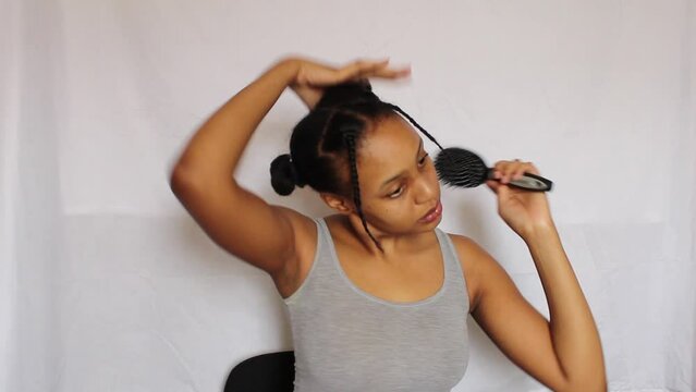 Young African Woman combing and making a ponytail on her 4C natural hair on a white background