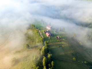 Fototapeta premium Mountain settlement in the Ukrainian Carpathians in the morning mist. Aerial drone view.