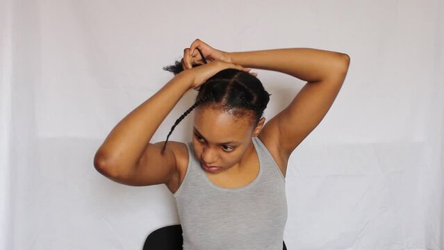 Young African Woman making a ponytail on her 4C natural hair on a white background