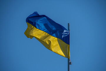 A Ukrainian flag flies against a cloudless sky