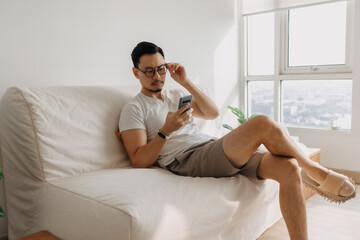 Fototapeta premium Middle age Asian man with long eye sight try to look at the smartphone.