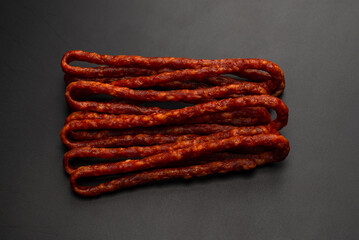 Cabanossi, dry sausage isolated on black background.