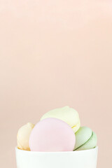 Sweet and colourful marshmallows looks like french macaroons in porcelain white coffee cup mug. Free space for text.