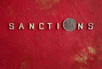 Wooden letters make up the word Sanctions with a one Russian ruble coin. The concept of sanctions...