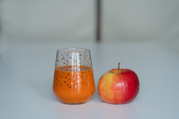 Ripe apple and carrot-banana juice on a bright kitchen table. Healthy foods