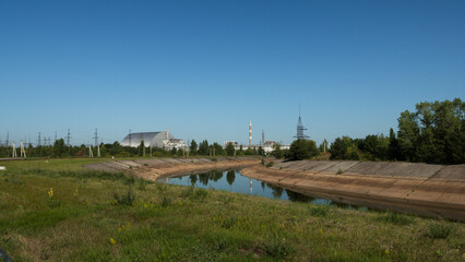 The fourth reactor of the Chernobyl nuclear power plant under a new safe sarcophagus. Exclusion Zone. Radiation. River landscape on a summer sunny day