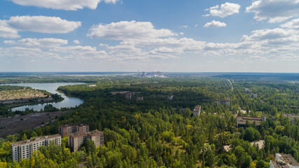 Fototapeta na wymiar Aerial view abandoned buildings and streets overgrown with trees in city Pripyat near Chernobyl nuclear power plant. Drone shot Exclusion Zone in summer. Reactor under the sarcophagus. Radiation