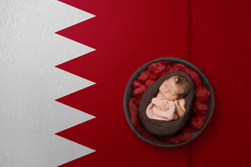 Newborn portrait on background in color of national flag. Patriotic photography concept. Bahrain