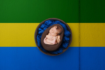 Newborn portrait on background in color of national flag. Patriotic photography concept. Gabon