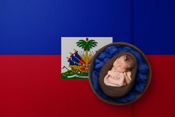 Newborn portrait on background in color of national flag. Patriotic photography concept. Haiti