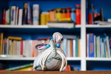 Ratte vor verschwommenem Bücherregal. Buch liebende graue Maus mit blauen Augen und rosa Ohren....