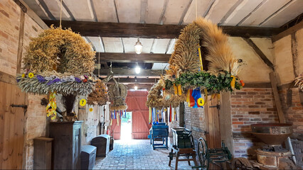 Erntedankfest Dekoration indoors. Getreideähren und geflochtene Kränze hängen an der Decke....