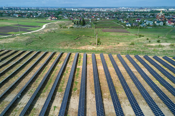 Aerial view of solar power plant on green field. Electric farm with panels for producing clean ecologic energy