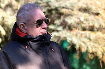 Portrait of senior man wearing glasses in the nature with natural light