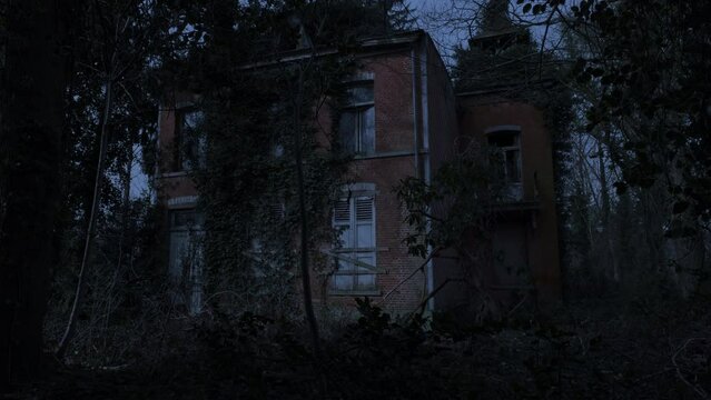Abandoned mansion ruin in a forest nighttime tilt up from the ground