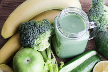 fresh green smoothie in glass bottle with vegetables on wooden background.vegan food, self care and...