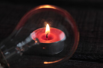 Bombilla con vela detrás y fondo oscuro