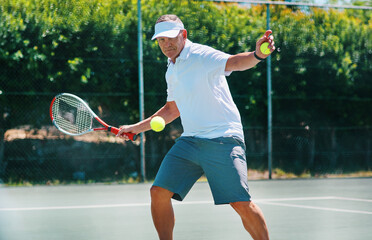 Staying healthy is a lifestyle. Cropped shot of a handsome mature man playing tennis alone on a court during the day. - Powered by Adobe