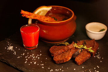 Restaurant serving of a dish - a pot of hodgepodge and black bread with a glass of alcohol