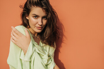 Close-up of fair-skinned young woman looking seriously at camera against red background. Brunette...