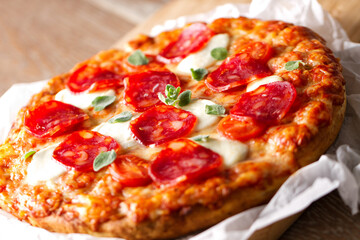 Pizza with pepperoni sausage and cheese on a wooden board on a wooden background